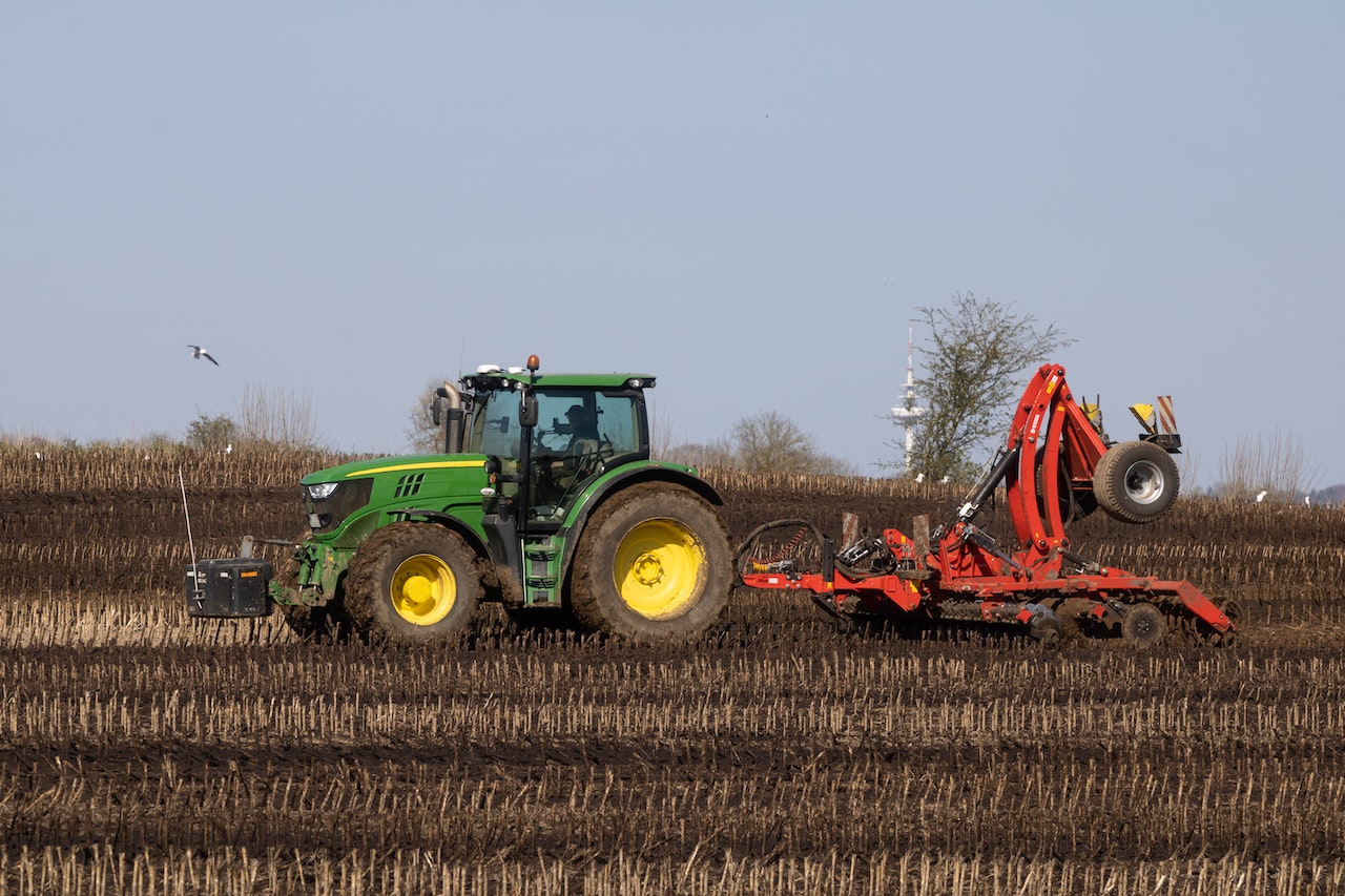 green tractor plowing on the field