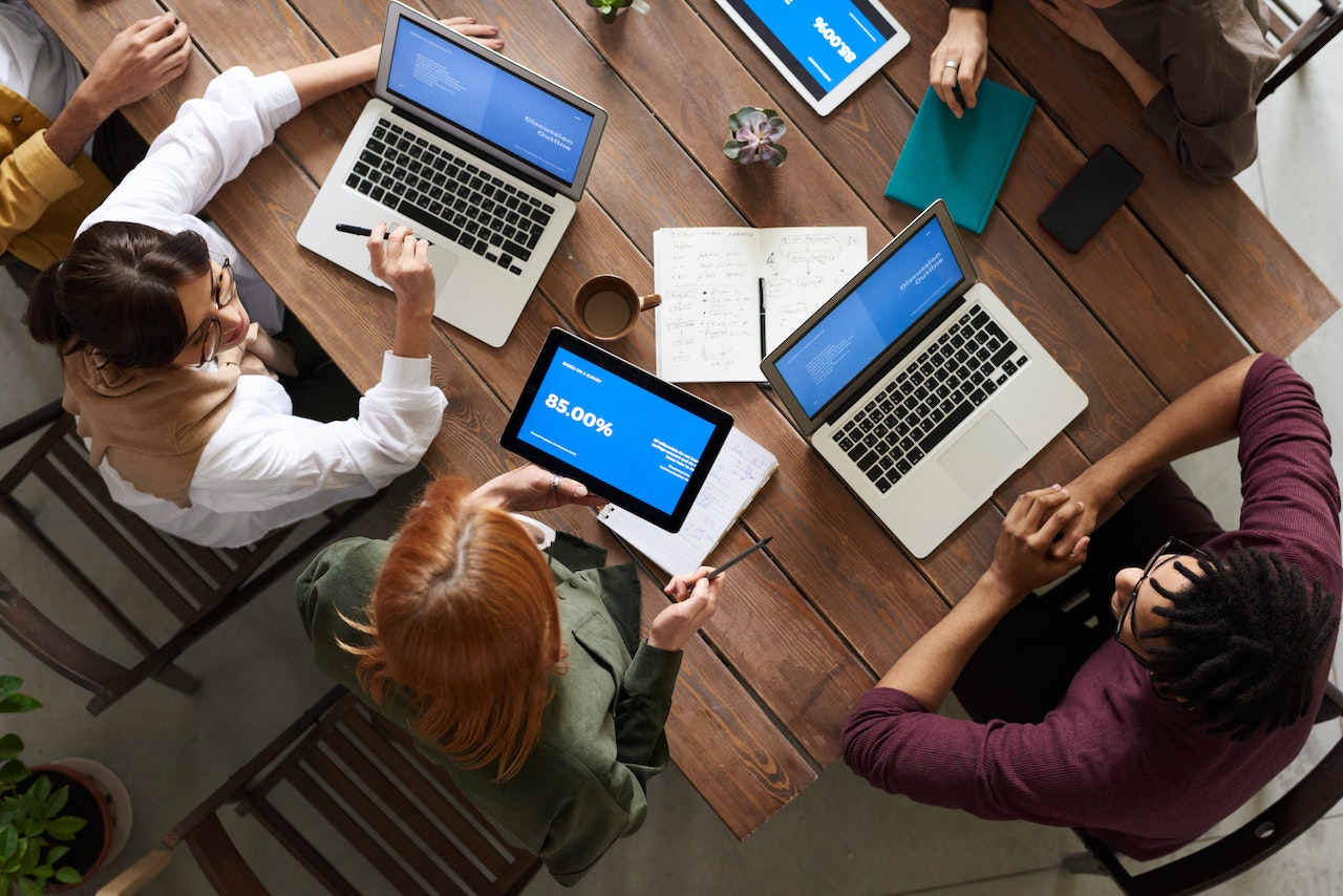 4 people are working together with their laptops, sitting on chairs